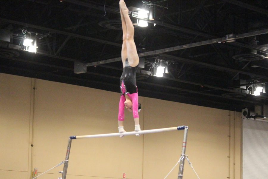 Addison Fishman, freshman, performing on bars during her gymnastics competition 