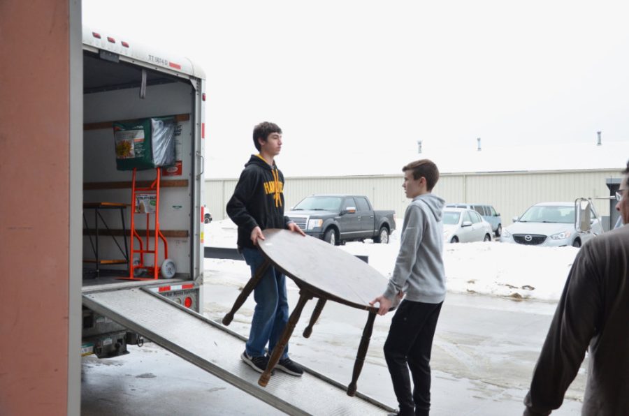 Two high school volunteers carry a recycled table into a moving van. This table will eventually be of use in someone’s kitchen. 