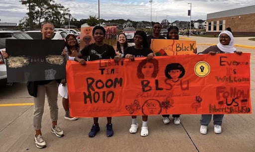 Liberty BLSU marches in the 2022 homecoming parade with banners they made.