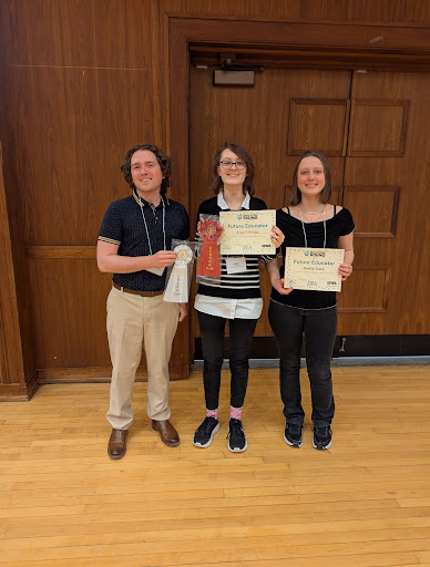 Zachary Lively with students Frey Kellogg, 11, and Gretta Core, 11,  showcasing the awards they won at a competition.